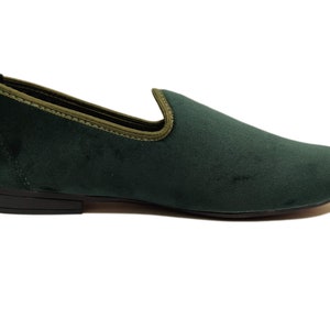 May include: A pair of dark green velvet loafers with a black rubber sole.