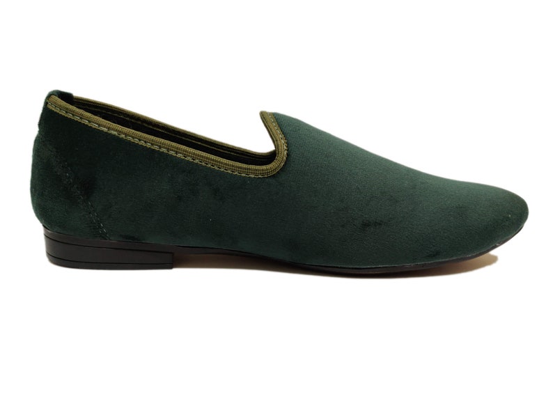 May include: A pair of dark green velvet loafers with a black rubber sole.