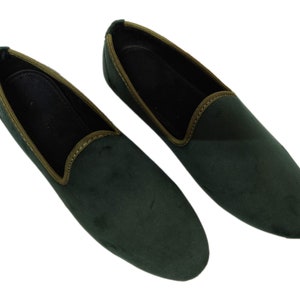 May include: A pair of dark green velvet loafers with a brown trim around the edge.