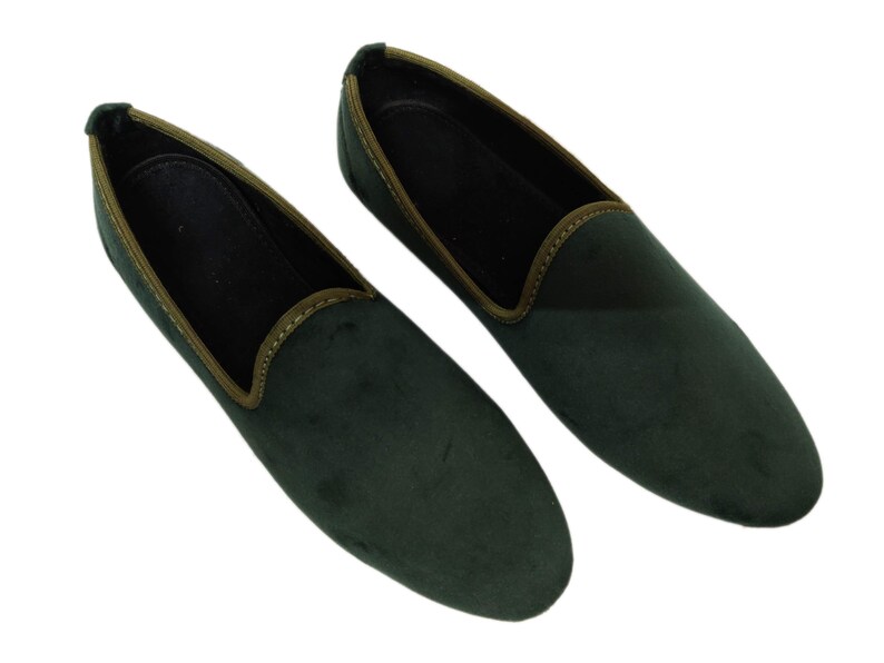 May include: A pair of dark green velvet loafers with a brown trim around the edge.