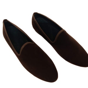 May include: A pair of brown velvet slippers. The slippers have a pointed toe and a slip-on design.