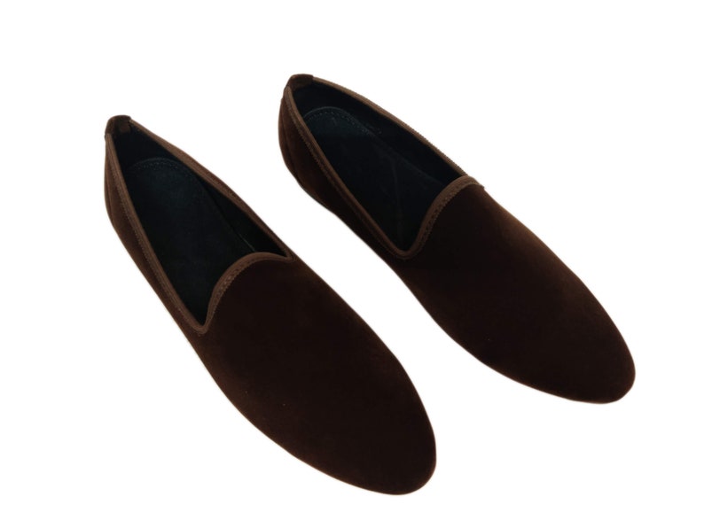 May include: A pair of brown velvet slippers. The slippers have a pointed toe and a slip-on design.