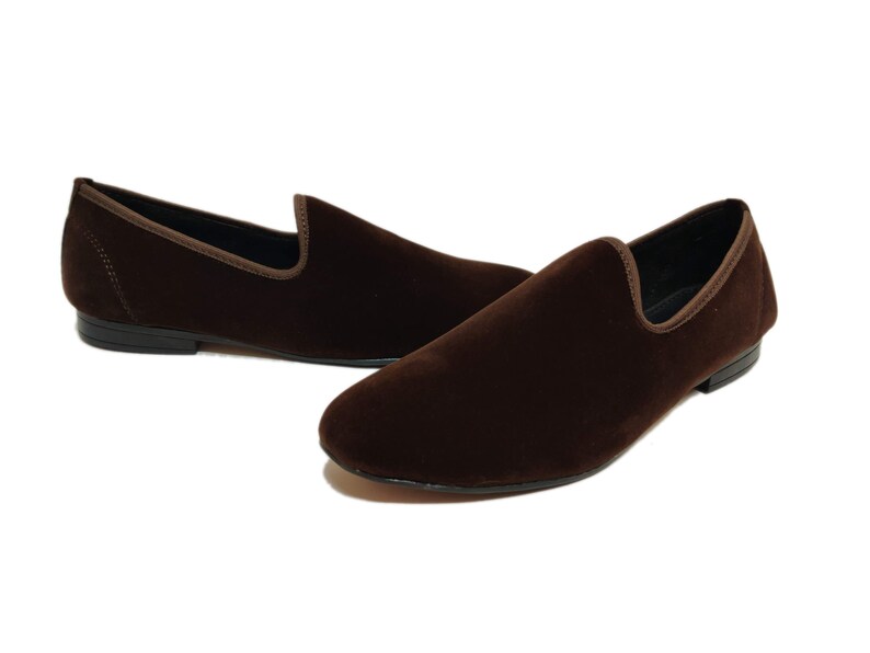 May include: A pair of brown velvet loafers with a pointed toe and a slip-on design.