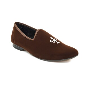 May include: A brown velvet loafer with a white embroidered fleur-de-lis design.