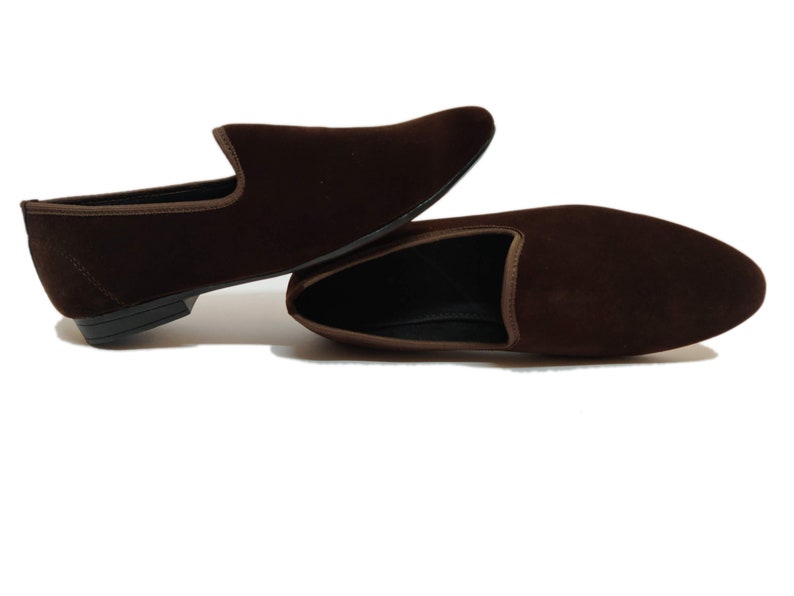 May include: A pair of brown velvet loafers with a pointed toe and a slip-on design.
