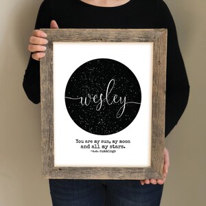 May include: A framed print with a black and white design of a starry night sky with the name "wesley" written in white script. The quote "You are my sun, my moon and all my stars. -e.e. cummings" is printed below the design.