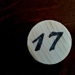 Puede incluir: Un c&iacute;rculo de madera blanco con el n&uacute;mero 17 escrito en negro.