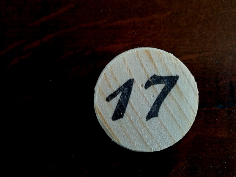 Puede incluir: Un c&iacute;rculo de madera blanco con el n&uacute;mero 17 escrito en negro.