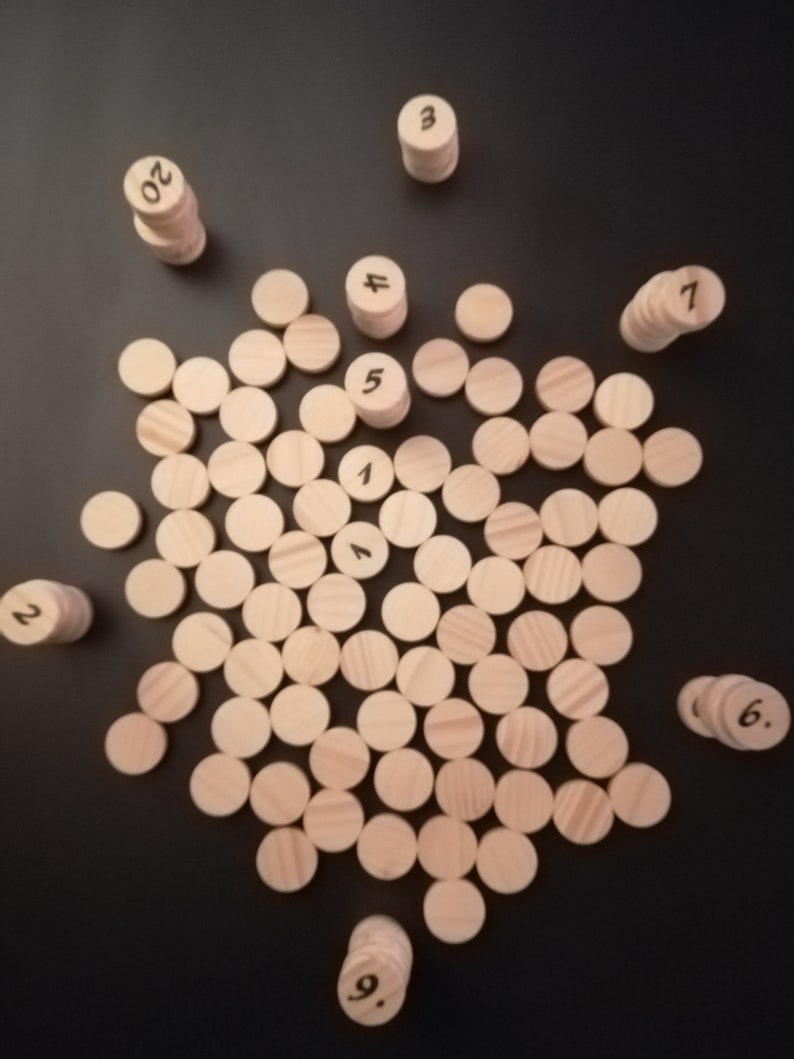 Puede incluir: Un conjunto de contadores de n&uacute;meros de madera, con los n&uacute;meros del 1 al 20, dispuestos sobre una superficie negra. Los contadores est&aacute;n apilados en pilas, con el n&uacute;mero hacia arriba.