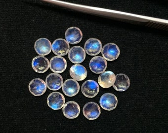 May include: A group of 16 round, iridescent moonstone cabochons in various sizes. The stones are a milky white color with a blue sheen.