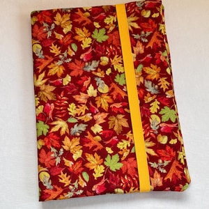 Puede incluir: Una funda de libro rectangular con un vibrante estampado de hojas de otoño en tonos rojos, naranjas, amarillos y verdes. Una banda elástica amarilla brillante asegura la funda. Diseñado para proteger libros o diarios.