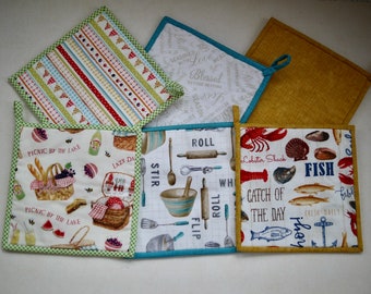 2 reversible pot holders - different patterns - fish and shells, picnic and pennants, kitchen utensils and writing