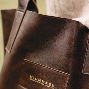 May include: A brown leather tote bag with a gold embossed logo that reads "MIUMMASH HANDCRAFTED SHOES & ACCESSORIES".