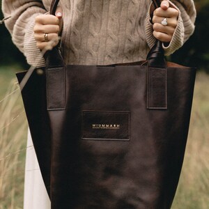 May include: A brown leather tote bag with a gold logo that reads "MIUMMASH handcrafted leather & accessories".