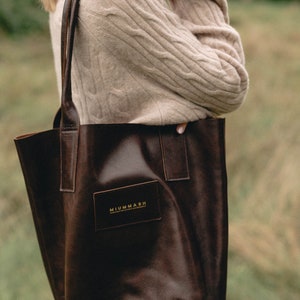 May include: A brown leather tote bag with a gold logo that reads "MIUMMASH HANDCRAFTED SINCE 2015".