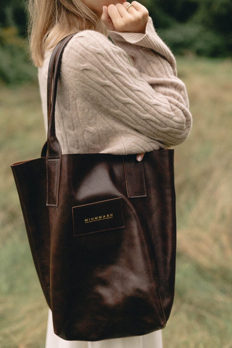 May include: A brown leather tote bag with a gold logo that reads "MIUMMASH HANDCRAFTED SINCE 2015".