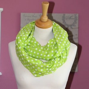 Könnte beinhalten: Ein grüner Infinity-Schal mit weißen Punkten. Der Schal ist aus einem weichen, bequemen Stoff gefertigt und perfekt, um jedem Outfit einen Farbtupfer zu verleihen.