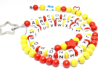 Könnte beinhalten: Eine bunte Alphabet-Perlenkette mit roten und gelben Perlen. Die Kette hat einen sternförmigen Metallverschluss und einen kleinen roten Sternanhänger.
