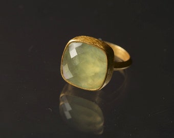 May include: A gold ring with a large, square, light green gemstone.