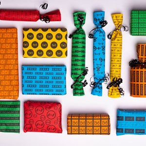 Könnte beinhalten: Sortiment an bunten Geschenkpapier mit verschiedenen Mustern und Zahlen. Die Muster umfassen 1x1, 2x2x2, 9-6, 9+8, 26-7, 10-10, 15:3, 3+3 und 50-25-7.