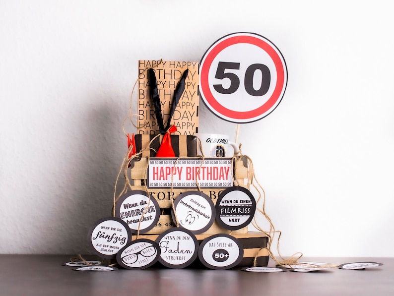 May include: A gift basket for a 50th birthday with a red and white speed limit sign with the number 50, a brown and black gift bag with the words "Happy Birthday" printed on it, a mug with the words "Old Time" printed on it, and several round black and white gift tags with humorous sayings.