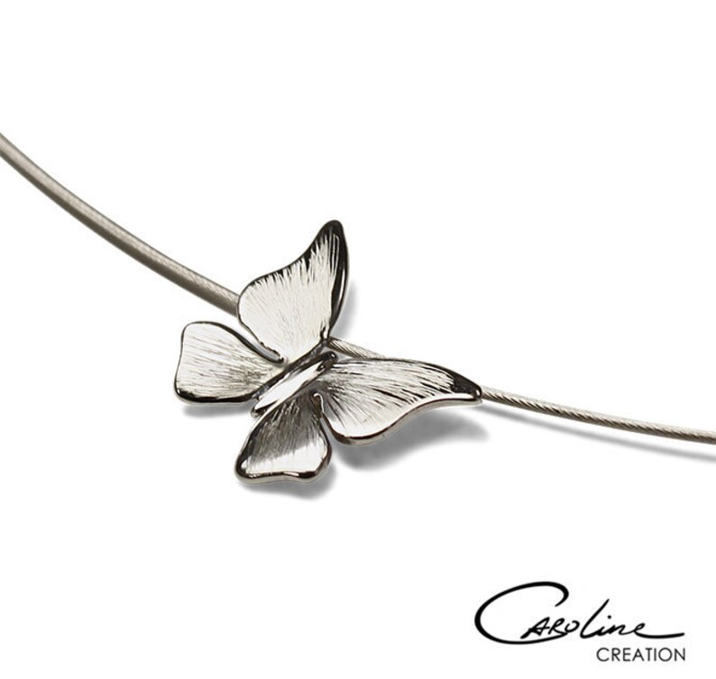 Puede incluir: Un collar de plata con un delicado colgante de mariposa. La mariposa es detallada y tiene un dise&ntilde;o tridimensional.
