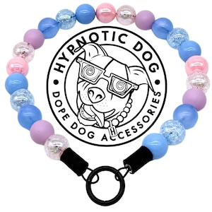 May include: A dog collar with a variety of colorful beads in shades of pink, blue, and purple. The collar features a black ring and clasp. The center of the collar has a circular logo with the text "HYPNOTIC DOG" and "DOPE DOG ACCESSORIES".