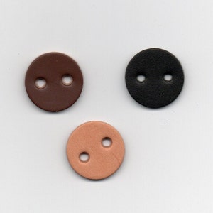 Puede incluir: Tres botones de cuero con dos agujeros cada uno. Los botones son marrón, negro y marrón claro.