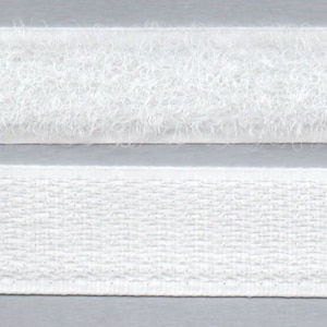Könnte beinhalten: Zwei Streifen weißes Klettband. Der obere Streifen hat eine weiche, flauschige Textur, während der untere Streifen eine gewebte Textur hat.