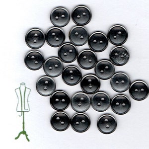 May include: A collection of 20 black metal buttons with two holes each. The buttons are arranged in a random pattern on a white background.