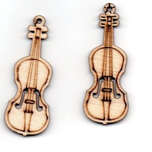 Puede incluir: Dos adornos de violín de madera, cada uno con un agujero en la parte superior para colgar. Los violines están detallados con un cuello tallado, cuerdas y agujeros de sonido.