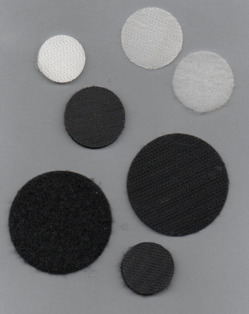 May include: Assortment of black and white fabric circles. The circles are of different sizes and have a textured surface.