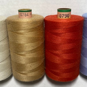 以下が含まれることがあります： 白、ベージュ、オレンジ、水色の4色の糸巻き。各糸巻きには、0778、0784、0790、0814という番号のラベルが付いています。