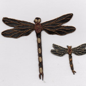 Peut inclure: Deux patchs de libellule brodés, l'un plus grand que l'autre. La plus grande libellule est noire avec des accents bruns et un corps segmenté blanc et brun. La plus petite libellule est noire avec des accents bruns et un corps segmenté brun.