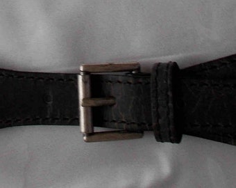 May include: A black leather belt with a silver buckle. The belt is designed with a unique, slightly curved shape.