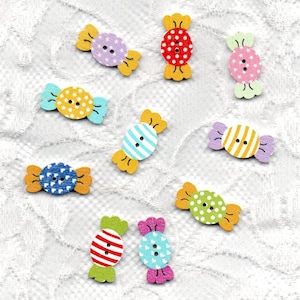 May include: Assortment of colorful wooden candy buttons with various patterns. The buttons are shaped like candy with a bow on each end. The buttons are in shades of blue, green, red, yellow, pink, and purple.