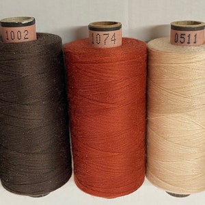 Może przedstawiać: Pięć szpulek nici w różnych kolorach: brązowy, ciemnobrązowy, pomarańczowy, beżowy i bordowy. Każda szpulka ma białą etykietę z nadrukowanym numerem: 432, 1002, 1074, 0511 i 0109.