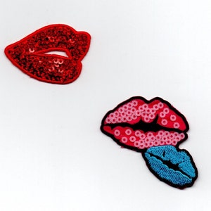 May include: Two red and pink sequined lips patches with a blue sequined lip patch. The patches are on a white background.