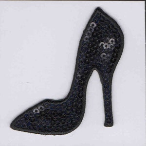 May include: Black sequined high heel shoe applique. The shoe is made of black sequins and has a pointed toe and a high heel.