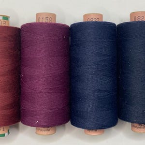 May include: Six spools of thread in various colours, including burgundy, purple, navy blue, and black. The spools are labelled with numbers, such as "0166", "0109", "0158", "0822", "0821", and "150/Tex 1".