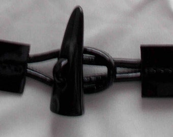May include: Black plastic toggle closure with two black straps and a black cord. The toggle is shaped like a teardrop.