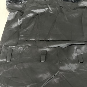 May include: A dark gray dress with a velvet bodice and a satin skirt. The skirt features two rectangular pockets with matching fabric tabs. The dress has a simple, elegant design.