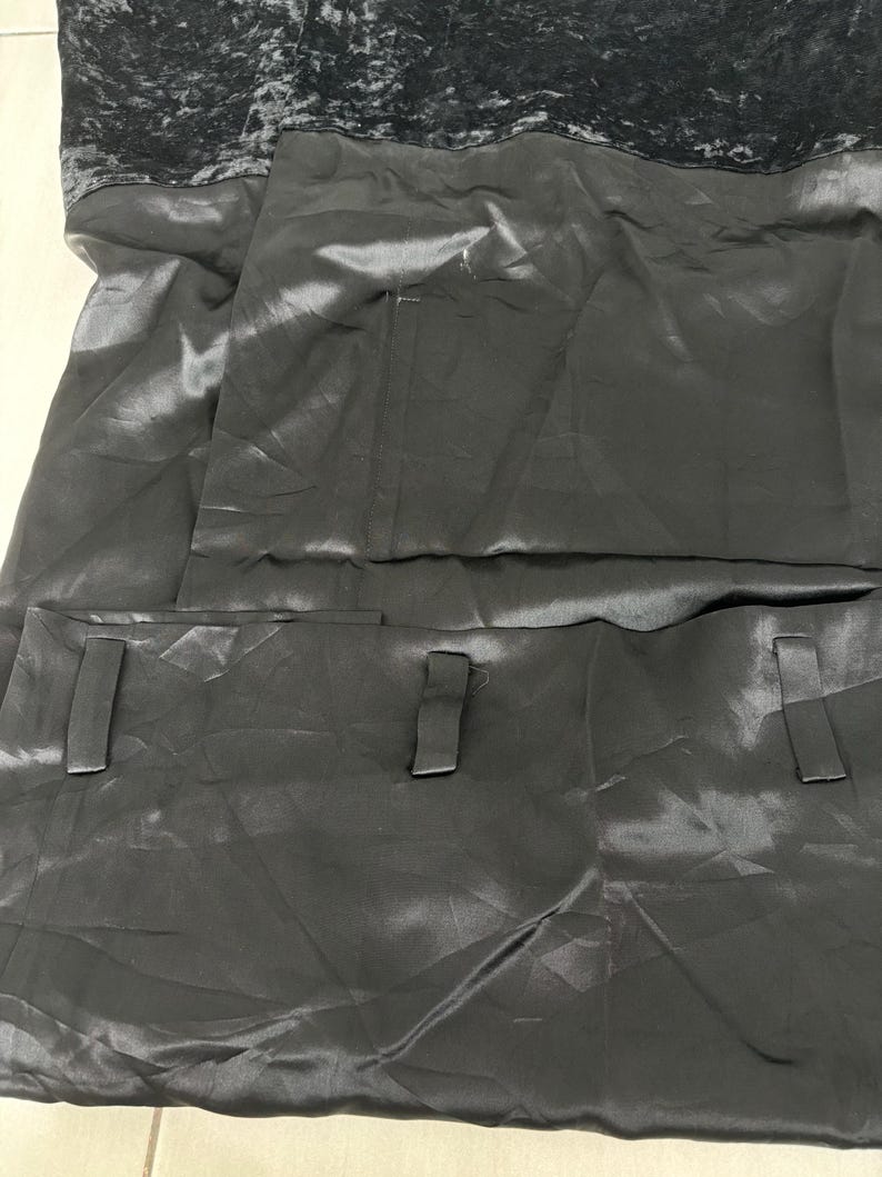 May include: A dark gray dress with a velvet bodice and a satin skirt. The skirt features two rectangular pockets with matching fabric tabs. The dress has a simple, elegant design.