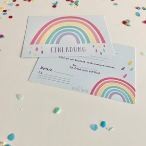 May include: A light blue invitation card with a rainbow design and the text "EINLADUNG" in black. The text "Bitte gib mir Bescheid, ob Du kommen kannst." is also included.