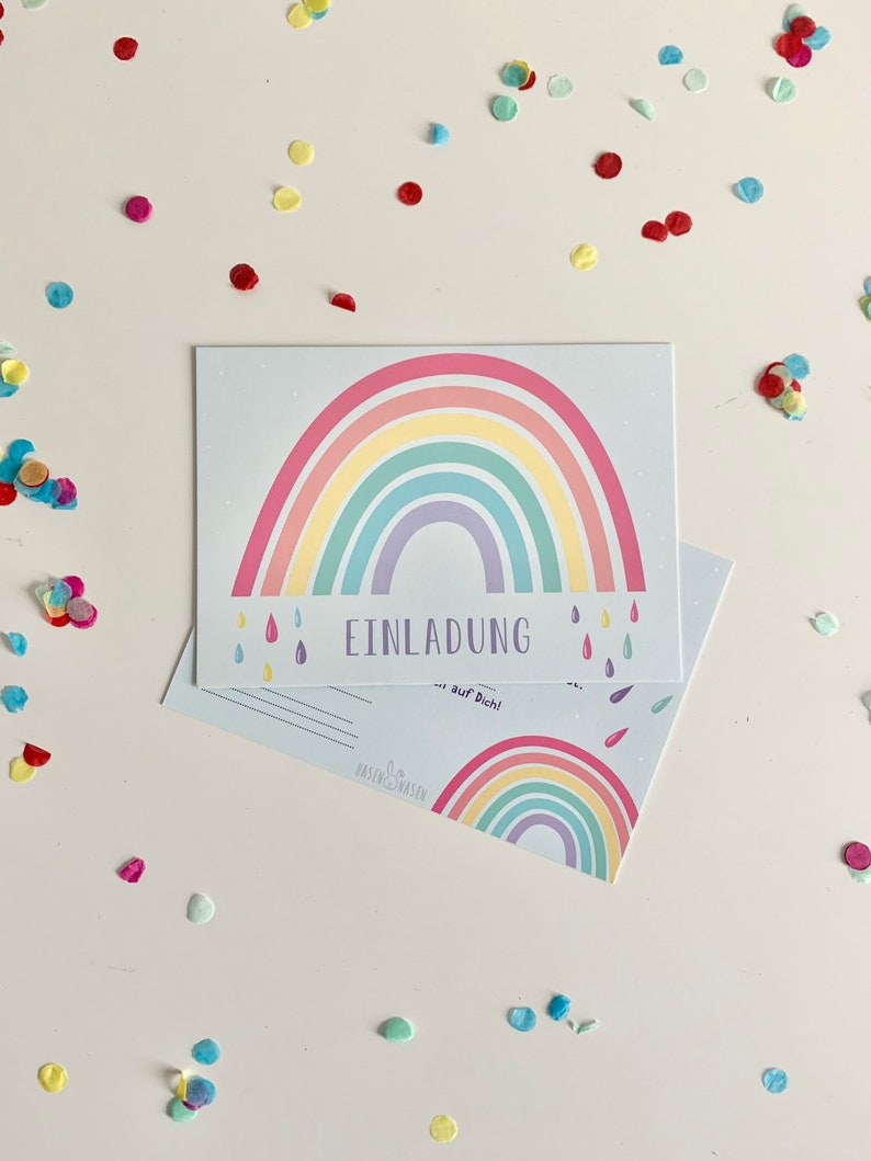 May include: A rainbow-themed invitation card with the text "EINLADUNG" and "auf Dich!" printed on it. The card features a colorful rainbow with raindrops and a white background.