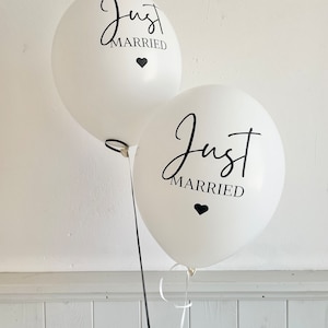 Peut inclure: Deux ballons blancs avec l'inscription noire "Just Married" et un petit c&oelig;ur noir.