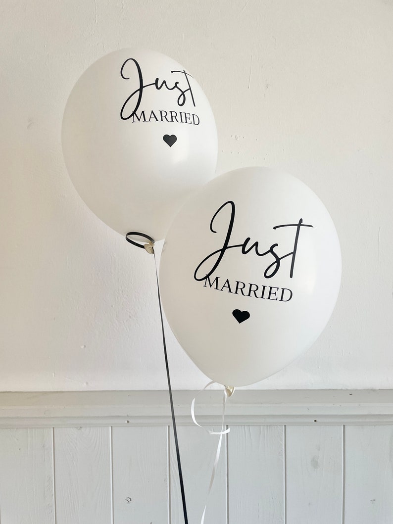 Peut inclure: Deux ballons blancs avec l'inscription noire "Just Married" et un petit c&oelig;ur noir.