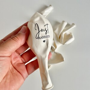 Peut inclure: Ballons en latex blancs avec le texte "Just Married" imprim&eacute; en &eacute;criture noire avec un petit c&oelig;ur.