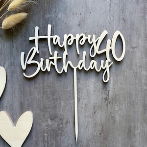 Könnte beinhalten: Ein Kuchenaufsatz aus Holz mit den Worten "Happy 40 Birthday" in Schreibschrift. Die Zahl 40 ist in einer einfachen, klaren Schriftart gehalten. Der Aufsatz hat einen langen, spitzen Stiel zum Einstecken in einen Kuchen. Der Hintergrund ist eine strukturierte graue Oberfläche.