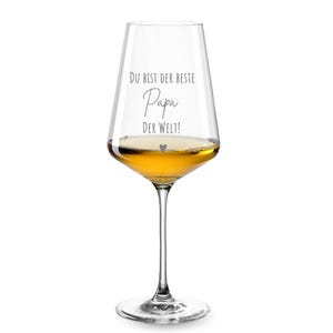 May include: A clear glass wine glass with a stem and a wide bowl. The glass is engraved with the text "Du bist der beste Papa der Welt!" which translates to "You are the best Dad in the world!" in English. The glass is filled with a light yellow liquid.